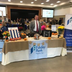 Man posing with Fidelity Bank table at expo