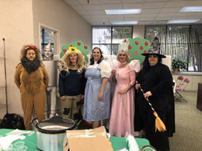 The team dressed up as the Wizard of Oz cast, a lion, the good & bad witches, the scarecrow, and Dorothy.
