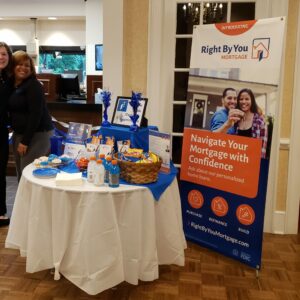 Two women smile beside a Right By You display