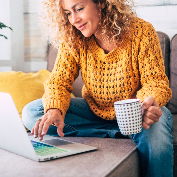 A woman relaxing with her laptop and a cup of coffee