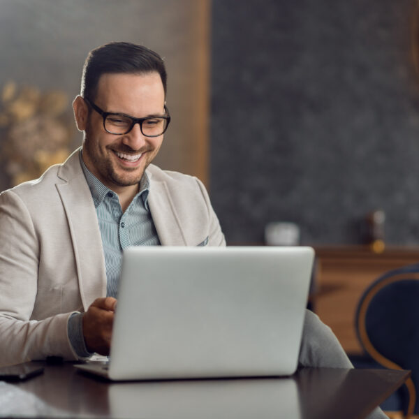 A man laughs as he looks at his computer, relaxed