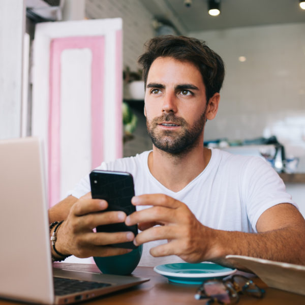 A man looking away from his phone in thought