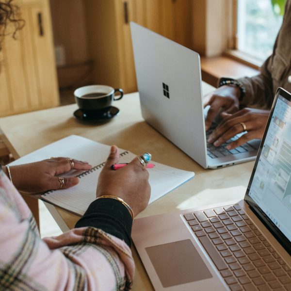 Two women work on laptops