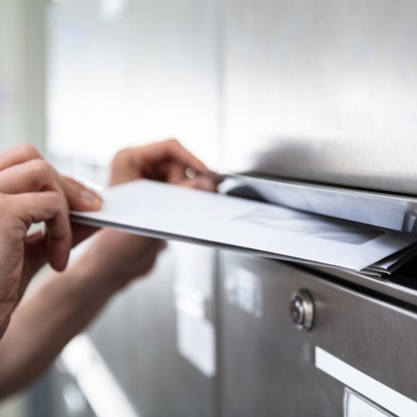 Human's Hand Inserting Letters In Mailbox