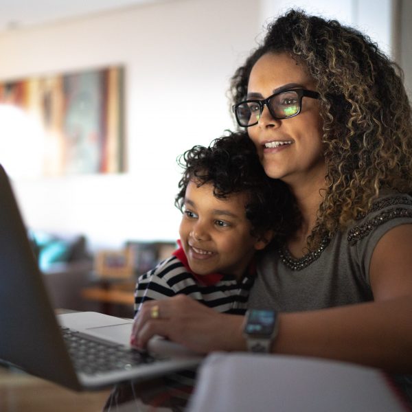 a woman looking at a laptop with her young son