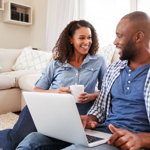 a couple sitting in the floor of a living room with a laptop