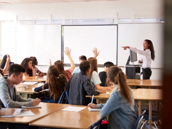 a teacher pointing to students with raised hands