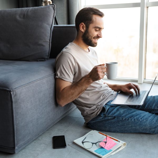 a young man sitting on the floor with a laptop