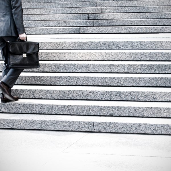 Man in business suit walking up stairs holding a briefcase