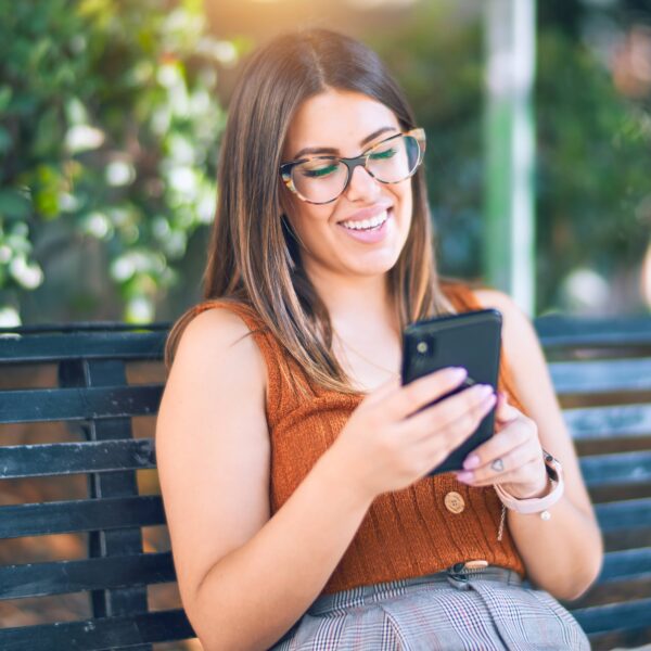 a young woman looking at her phone on a park bench