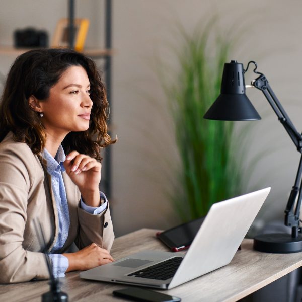 a woman looking up from her laptop at her desk