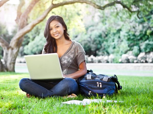 a student sitting outside on the grass with her laptop
