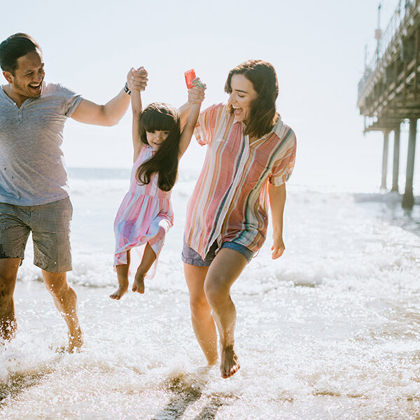 Young parents walking with their daughter in the ocean