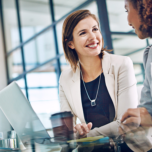 Two young businesswomen using a laptop together at work