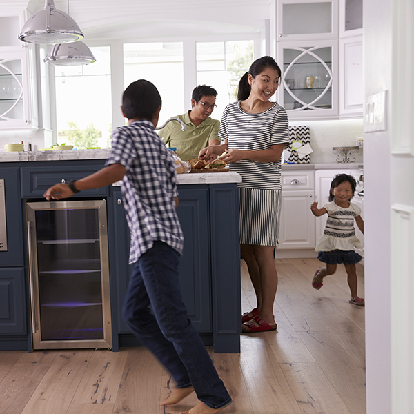 Parents Prepare Food As Children Play In Kitchen