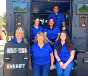employees posing with a sheriff truck 