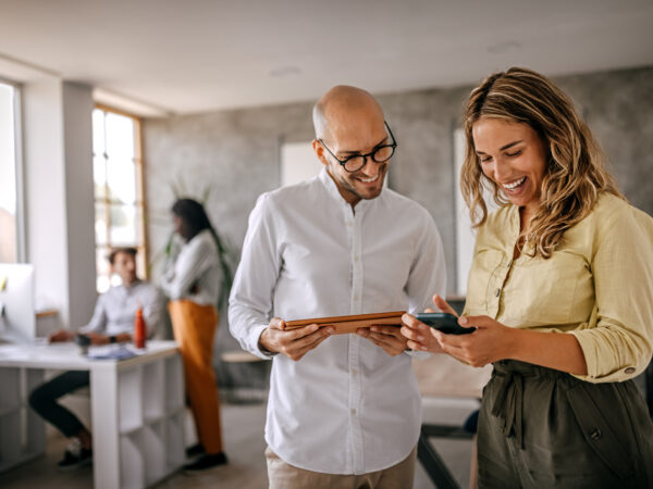 Businessman and businesswoman smiling looking at phone