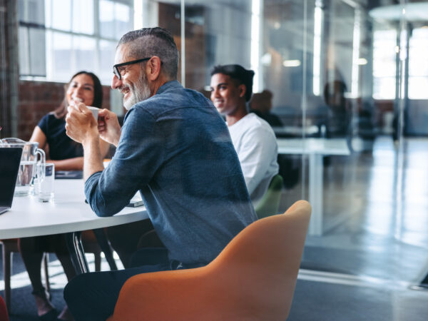 Happy mature businessman attending a meeting with his team