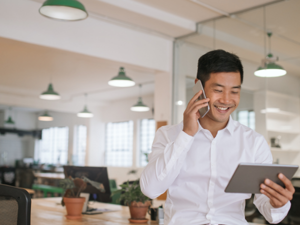 man talking on cell phone and using ipad