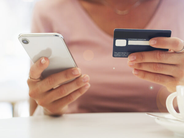Woman looking at cell phone and holding debit card
