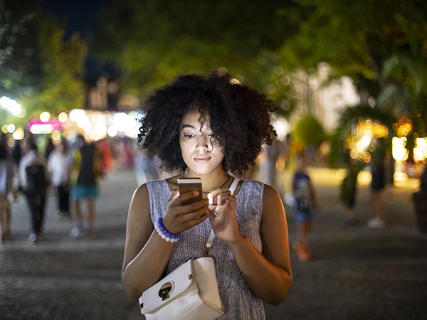 African American women wearing a purse looking at phone