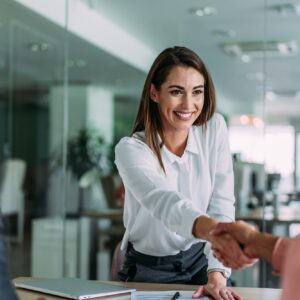 Businesspeople handshaking across the table during a meeting