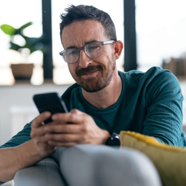 Middle aged man looking at his phone while sitting on a couch