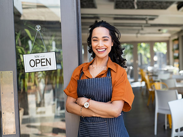Smiling small business owner standing in the doorway of her new cafe